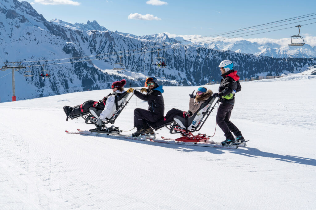 2 personnes handicapées font du handiski avec des moniteurs, grâce à une station de ski adaptée